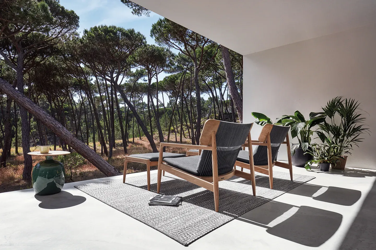 two archi lounge chairs with ottoman and deco rug and blow side table on terrace overlooking trees