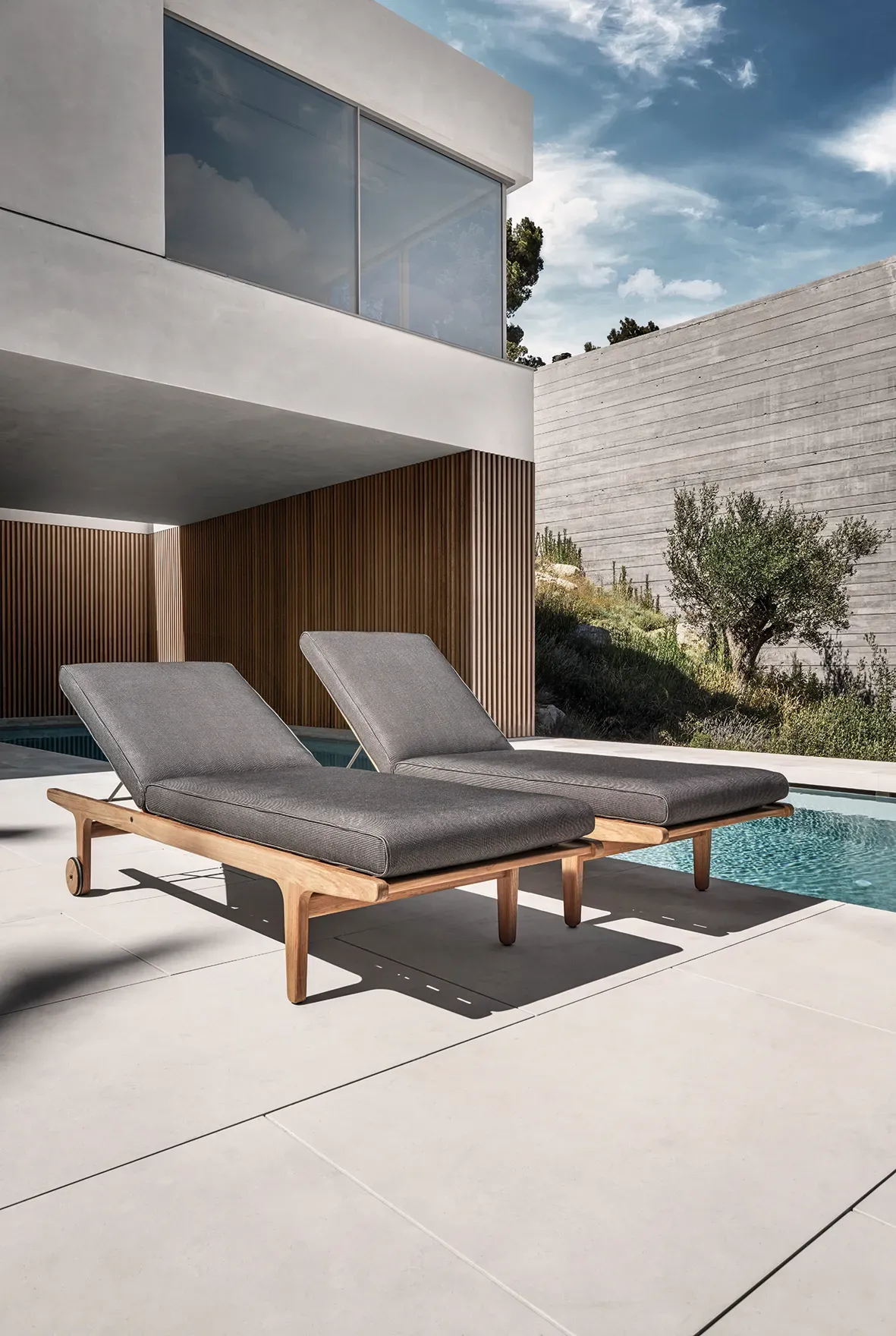 bay loungers on terrace next to house with pool