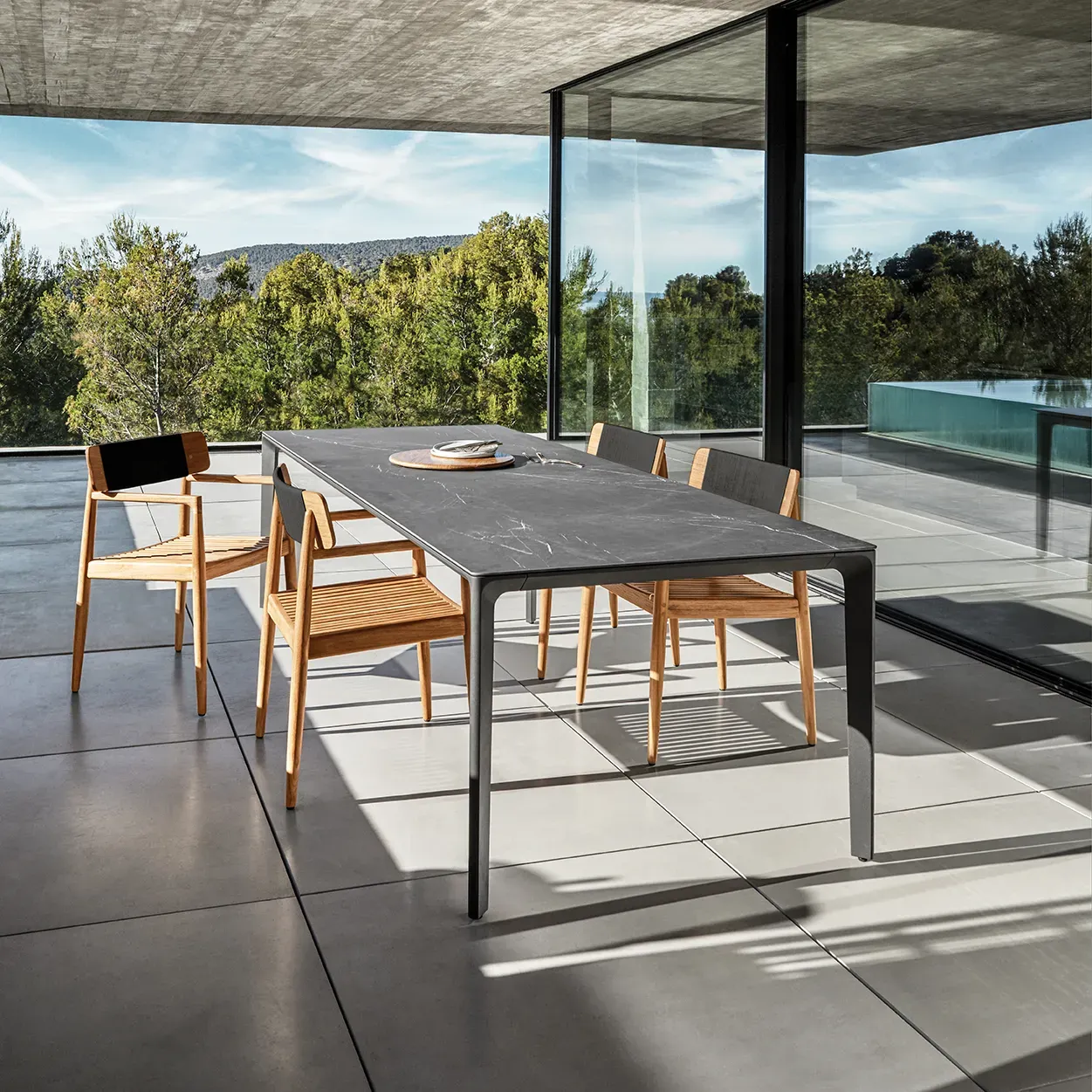 four archi dining chairs surround a carver ceramic top dining table in an architectural setting