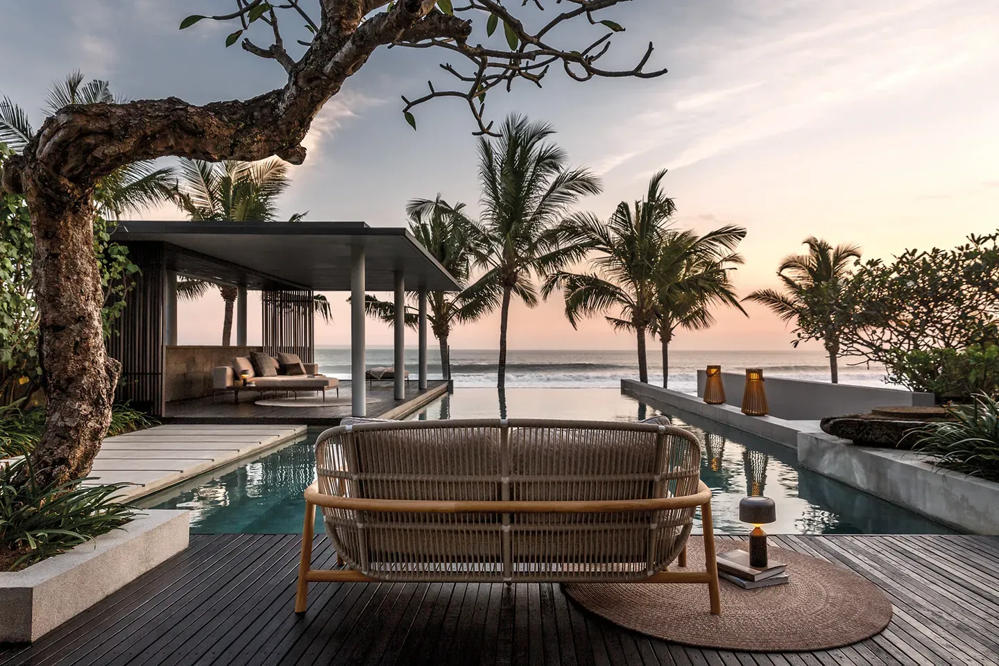 fern low back sofa and deco rug on decking overlooking a pool and sea view with ambient ray lanterns in the background