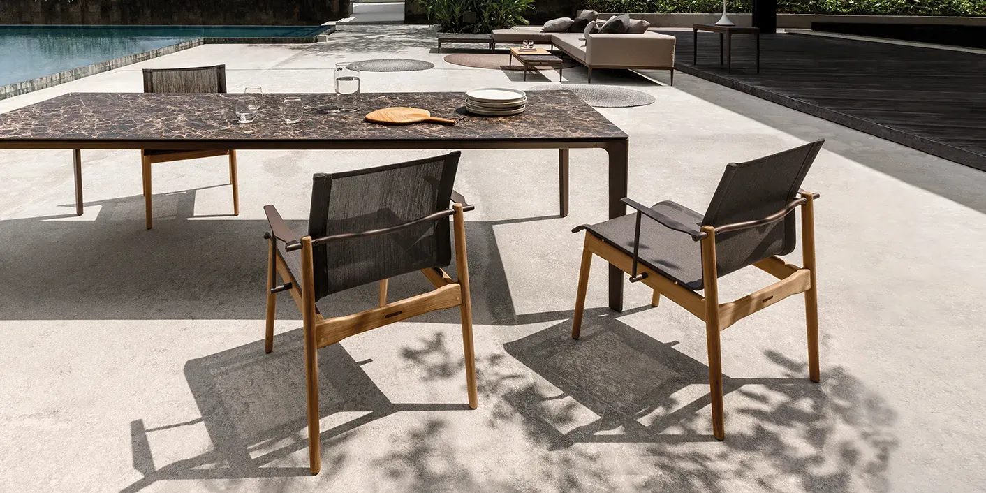 three sway teak dining chairs surround af carver ceramic dining table with poll and at lounge set in the background