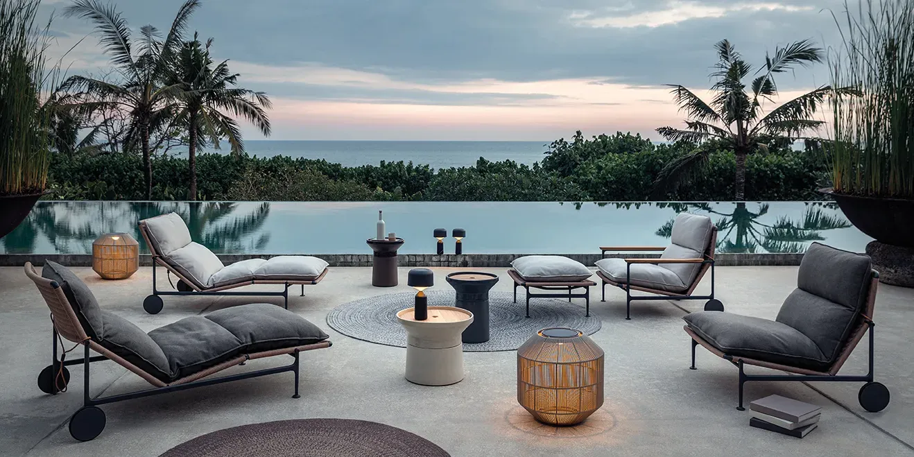 zenith seating group with deco rugs ambient nest and ambient pebble lamps and coso tables on a pool side terrace in the evening